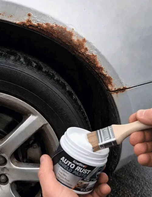 Applying brush-on rust protection paste to a car wheel arch